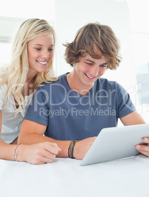 A couple smiling as they use a tablet