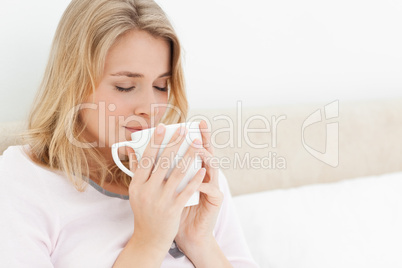 Woman with a cup rasied to her face, eyes closed, taking in the