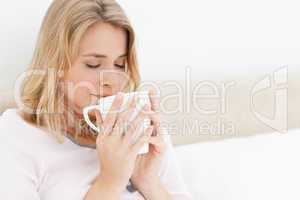 Woman with a cup rasied to her face, eyes closed, taking in the