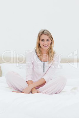 Woman sitting with folded legs on the bed