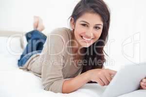 Woman uses tablet as she smiles looking straight ahead, while ly