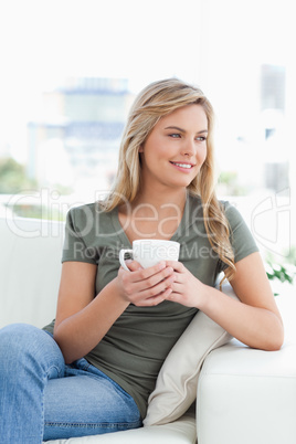 Woman with cup in hands, smiling and looking to the side