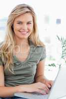 Close up, woman using a laptop while looking forward and smiling