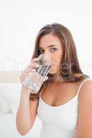 Close up, woman taking a drink from a glass while looking forwar