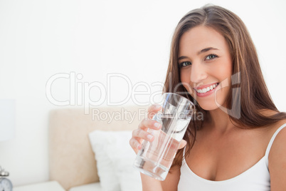 Woman smiling as she holds a glass of water,