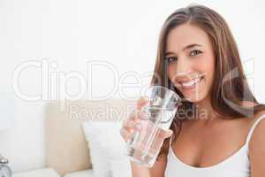 Woman smiling as she holds a glass of water,