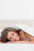 Close up, woman at the end of the bed smiling, with her head on