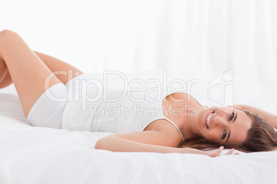 Woman lying on her back smiling while lying on the bed
