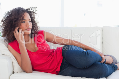 Woman lying on the couch, on her phone looking to the side