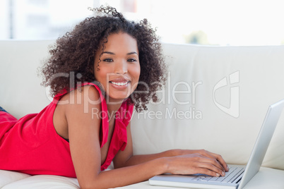 Woman lying forward on a couch with her laptop in front of her