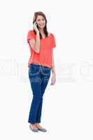 Teenager standing against a white background while giving a call