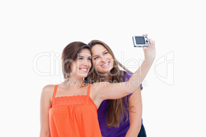Beaming teenager photographing herself and a smiling friend