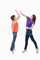 Two teenagers jumping while trying to join their hands