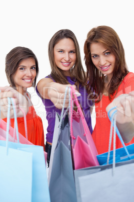 Smiling young women showing their purchases in front of the came