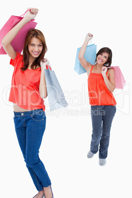 Teenage girl following her friend after shopping against a white