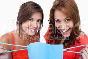 Two teenage girls holding a purchase bag while smiling