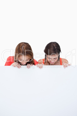 Teenagers looking at a blank poster while leaning their head for