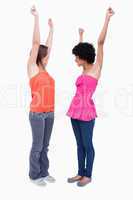 Two dynamic teenagers raising their arms in satisfaction