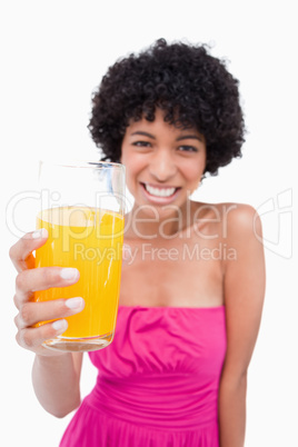 Glass of orange juice being held by a young smiling woman