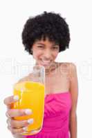 Glass of orange juice held forward by an attractive teenage