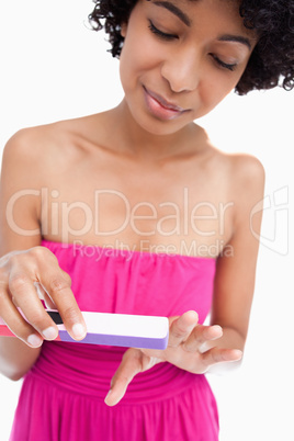 Young woman attentively filing her nails against a white backgro