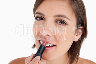 Young woman applying lipstick while looking at the camera