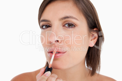 Young woman applying lip gloss with the brush included