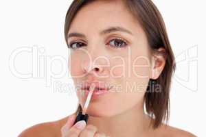 Young woman applying lip gloss with the brush included