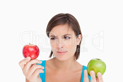 Teenage holding two apples and looking at the red one