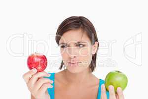 Teenage holding two apples and looking at the red one
