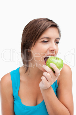 Teenager looking on the side while eating a green apple