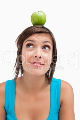 Attractive young woman standing upright with a green apple on he