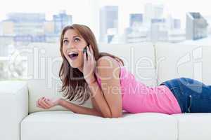 Teenage girl enjoying her phone call while lying on a white sofa