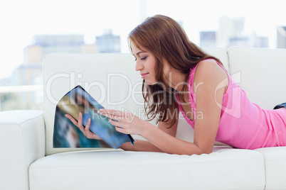 Teenage girl reading a magazine while lying on a sofa