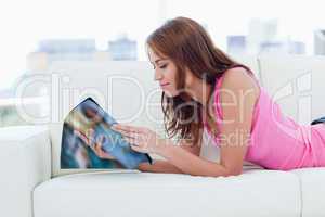 Teenage girl reading a magazine while lying on a sofa