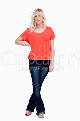 Serious fair-haired teenager standing with her legs crossed