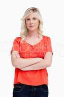 Serious fair-haired young woman standing upright with her arms c