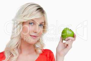 Attractive woman holding a green apple while looking at the came