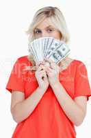 Attractive woman hiding her face behind dollar bank notes