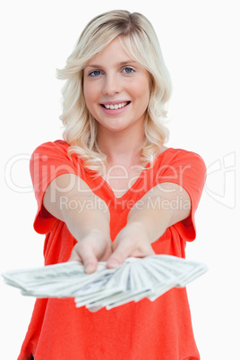Smiling woman holding a fan of dollar notes in her hands