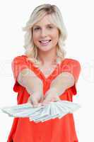 Smiling woman holding a fan of dollar notes in her hands