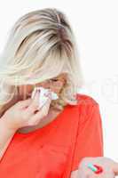 Young woman sneezing while holding some tablets