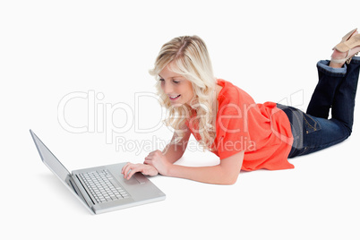 Woman lying down with legs crossed while using her laptop