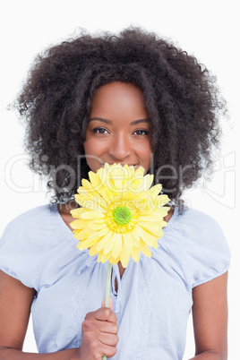 Teenage girl hiding her mouth behind a yellow flower