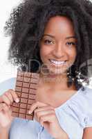 Smiling young woman with curly hair holding a chocolate bar