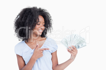 Young woman closing her eyes while pointing her finger on dollar