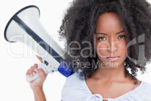 Young serious woman holding a megaphone behind her