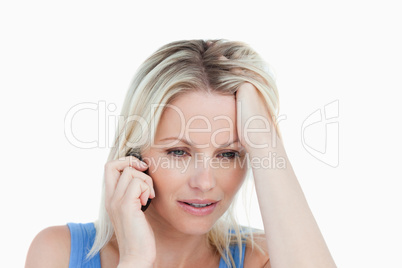 Serious woman talking on the phone with her hand on her forehead