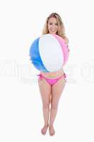 Smiling young woman holding a beach ball in front of her