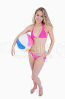 Smiling blonde teenager holding a beach ball under her arm